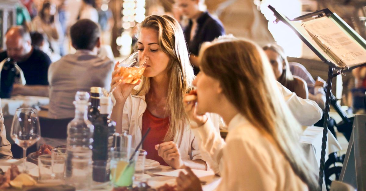 Friends dining in a cozy Italian restaurant, enjoying drinks and food in a lively atmosphere.